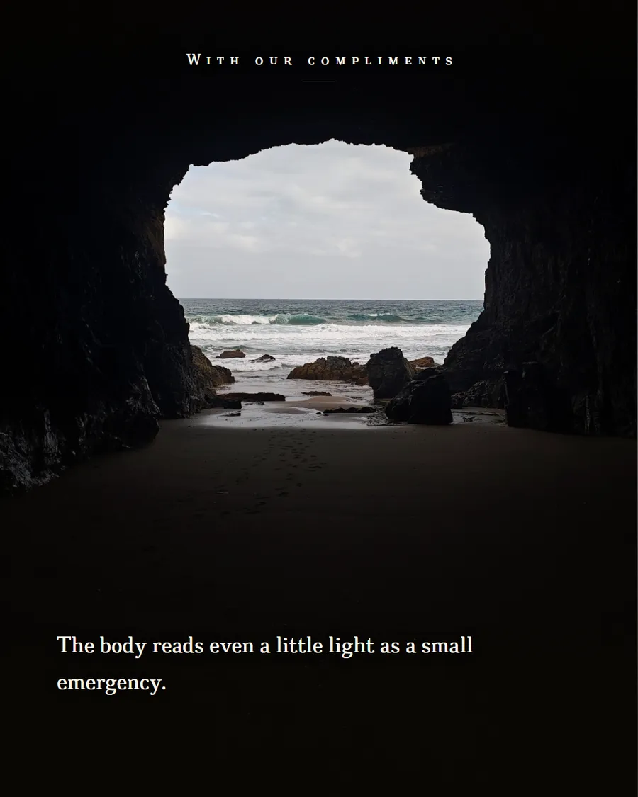 Looking out of a dark sea cave towards a bright beach and breaking waves