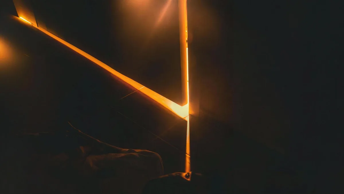 A blade of orange light spilling under and around a bedroom door in a dark room