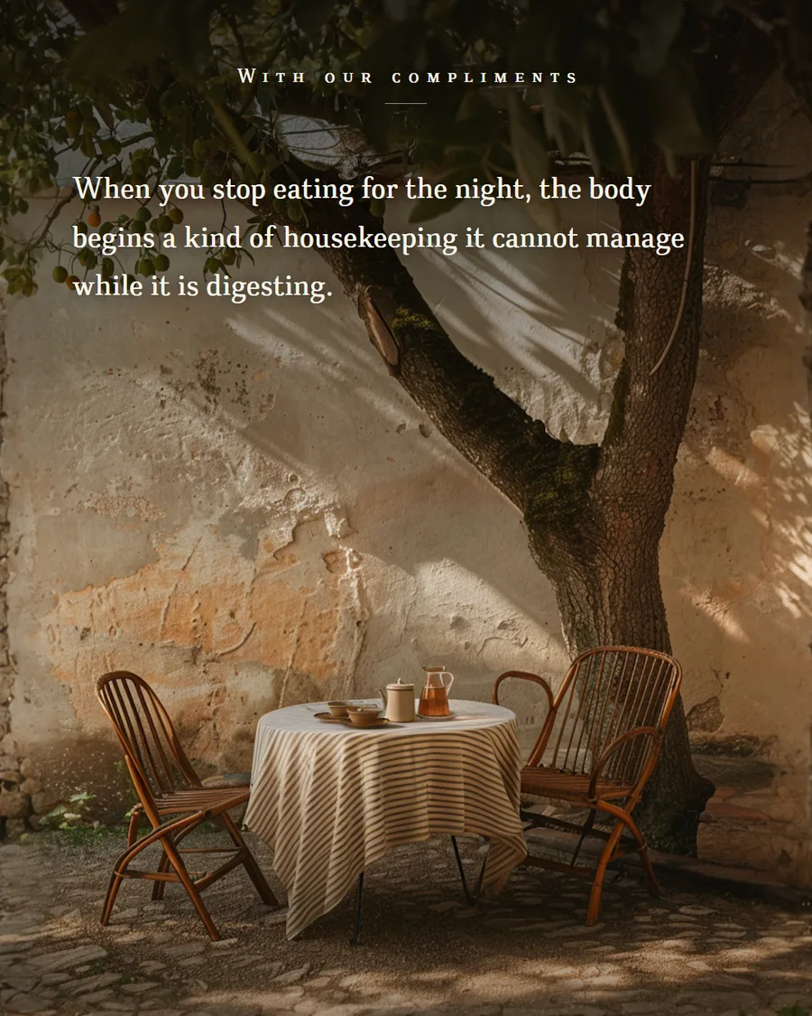 A small table laid under an olive tree against a sunlit plaster wall
