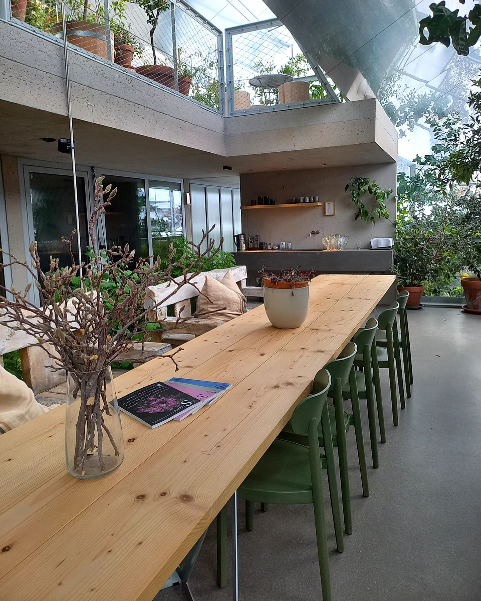 The long shared table and kitchen inside the planted Glasshaus