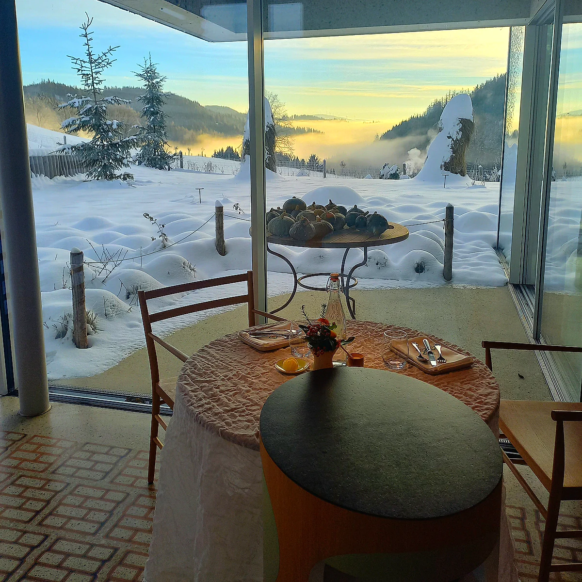 A table inside a Glasshaus cabana at Steirereck am Pogusch, looking across deep snow to the mountain valley