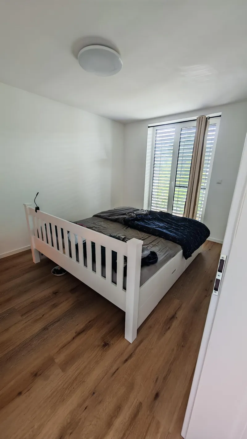 A bed pulled to the middle of the room, away from the wall wiring
