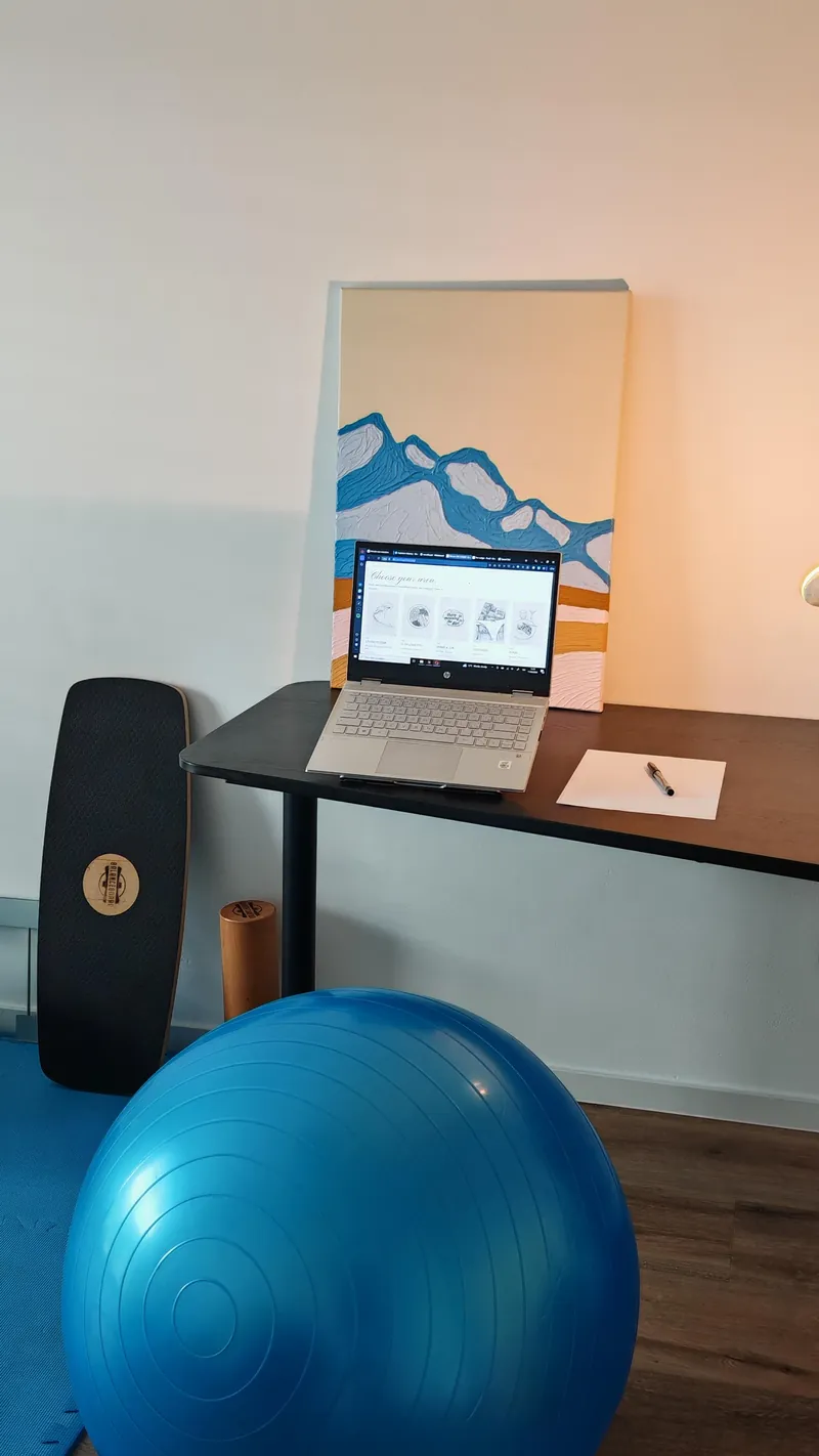 A home office desk with a warm task lamp and something living in the eye-line